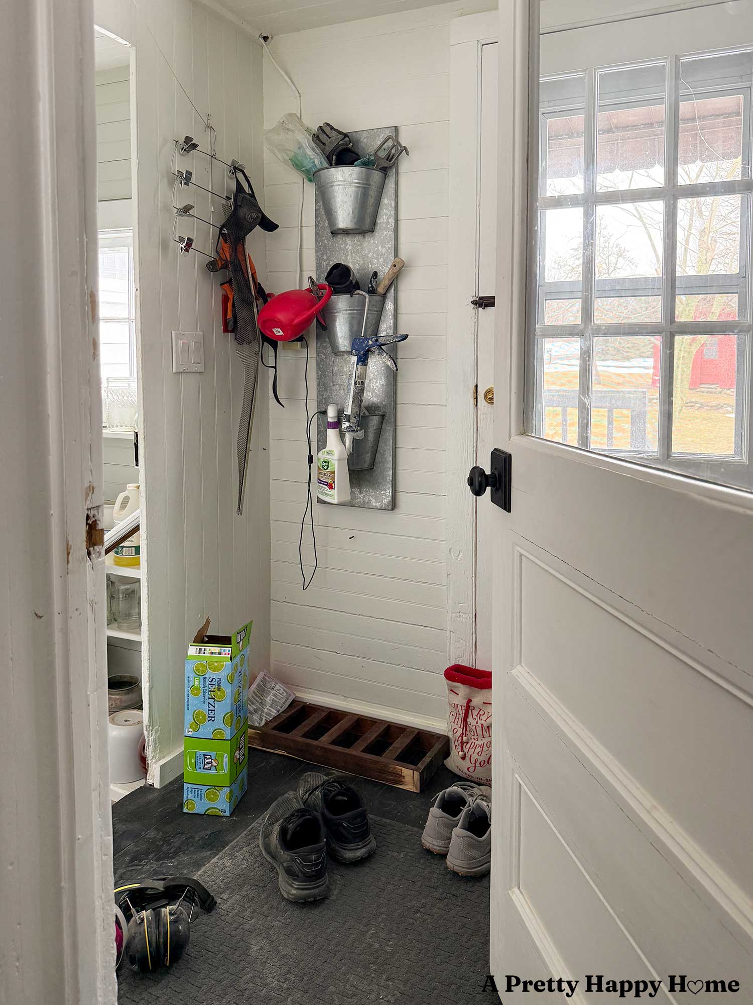 an organized back porch being used as a utility room with a silver planter being used as a shelf for gardening supplies