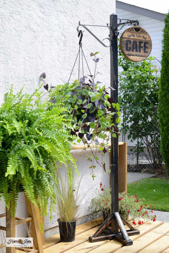 wooden coat rack repurposed as a hanging plant stand on a deck