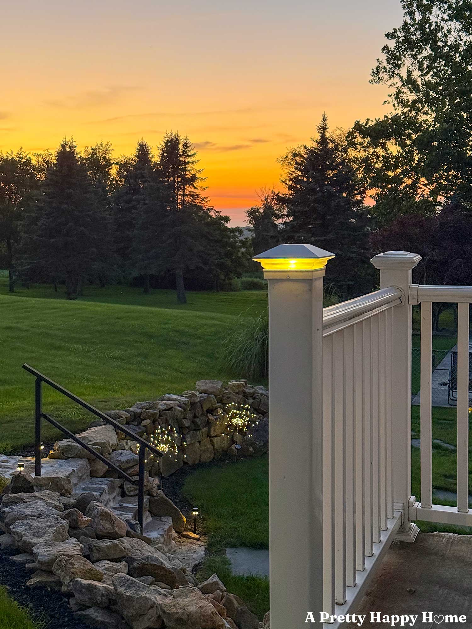 porch railing with solar post cap in front of a sunset with an orange sky