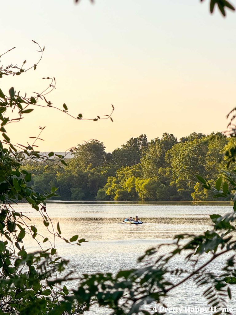 canoe on a calm lake at dusk with green trees in the background and foreground