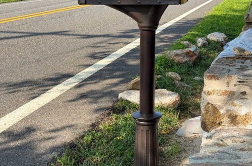 fancy looking oil rubbed bronze mailbox standing in front of a stone wall under construction