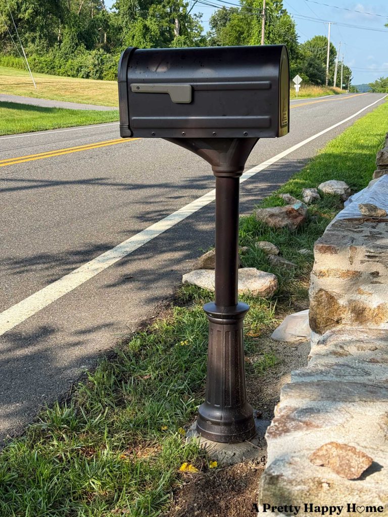 fancy looking oil rubbed bronze mailbox standing in front of a stone wall under construction