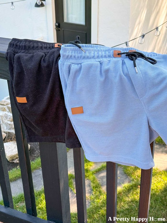a pair of black waffle knit shorts and blue waffle knit shorts hanging over a black deck railing