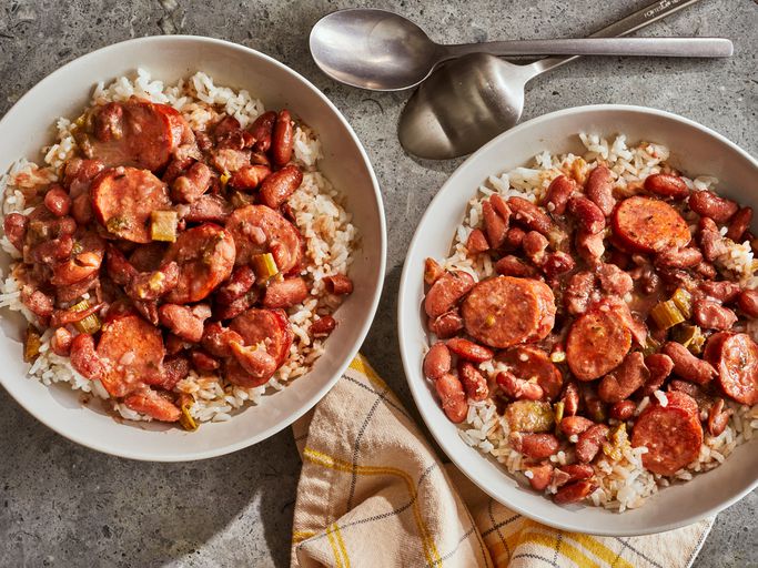 two bowls of Louisiana red beans an rice next to spoons and napkins