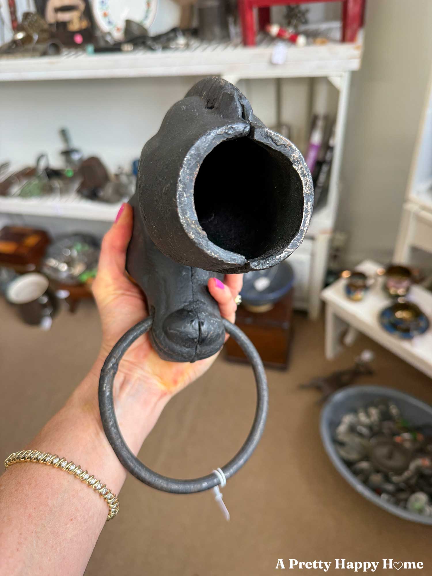 bottom view of an antique horse head hitching post that shows the seam where the two casts were joined together, the unevenness of the metal poured in the mold, and wear from a horse pulling on the post to make the base slightly misshapen.