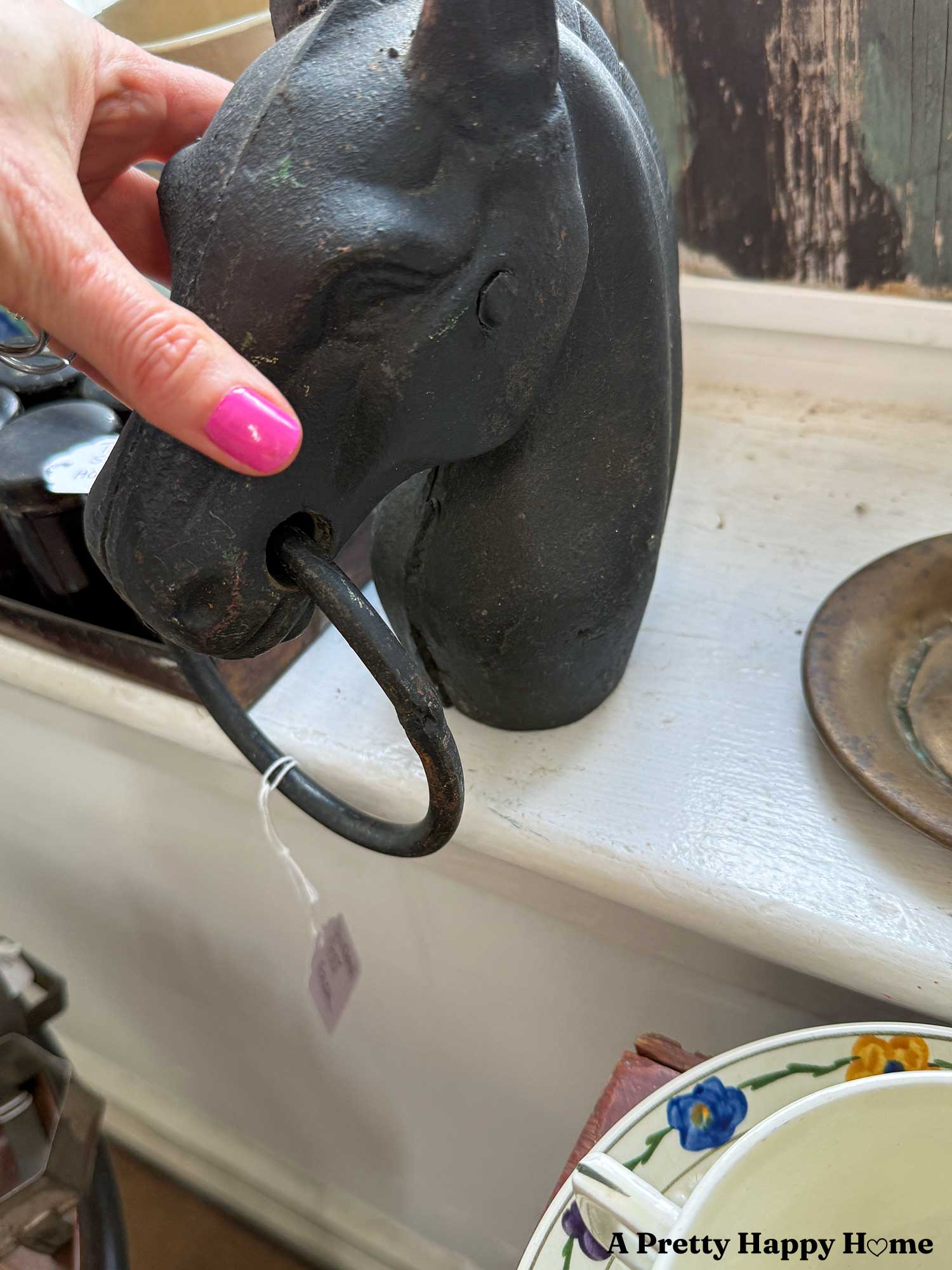 side view of an antique cast iron horse head finial for a hitching post that shows a pin near the horse's eye that would have been used to hold the two sides of the cast together while the blacksmith sealed the seam. Probably dates back to between 1880 and 1910.