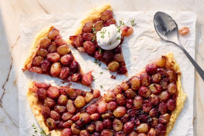 balsamic grape tart cut into slices and served with a dollop of balsamic whipped cream