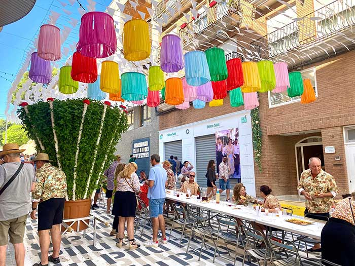basil festival in Betera Spain with colored lanterns hanging over a table and a giant basil plant in the background