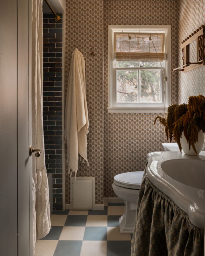 bathroom with moody natural colors, a checkered floor, and a towel hanging next to a green-tiled shower