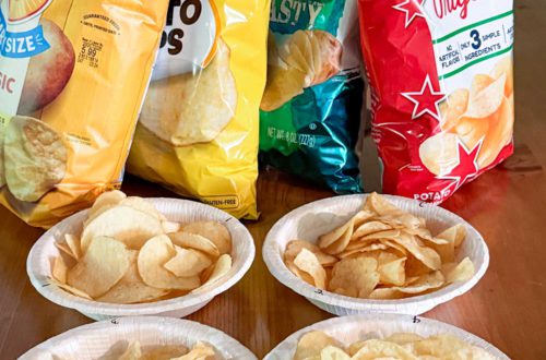 Bag of classic potato chips by Lays, Great Value, Herrs, and Utz lined up in front of numbered paper bowls filled with chips for a potato chip taste test